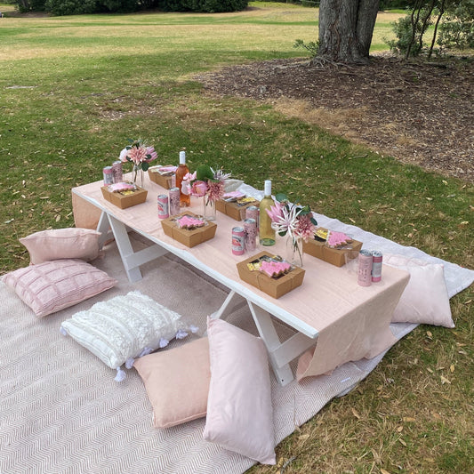 Pink and neutral mix of low picnic tables with rugs and cushions and florals 