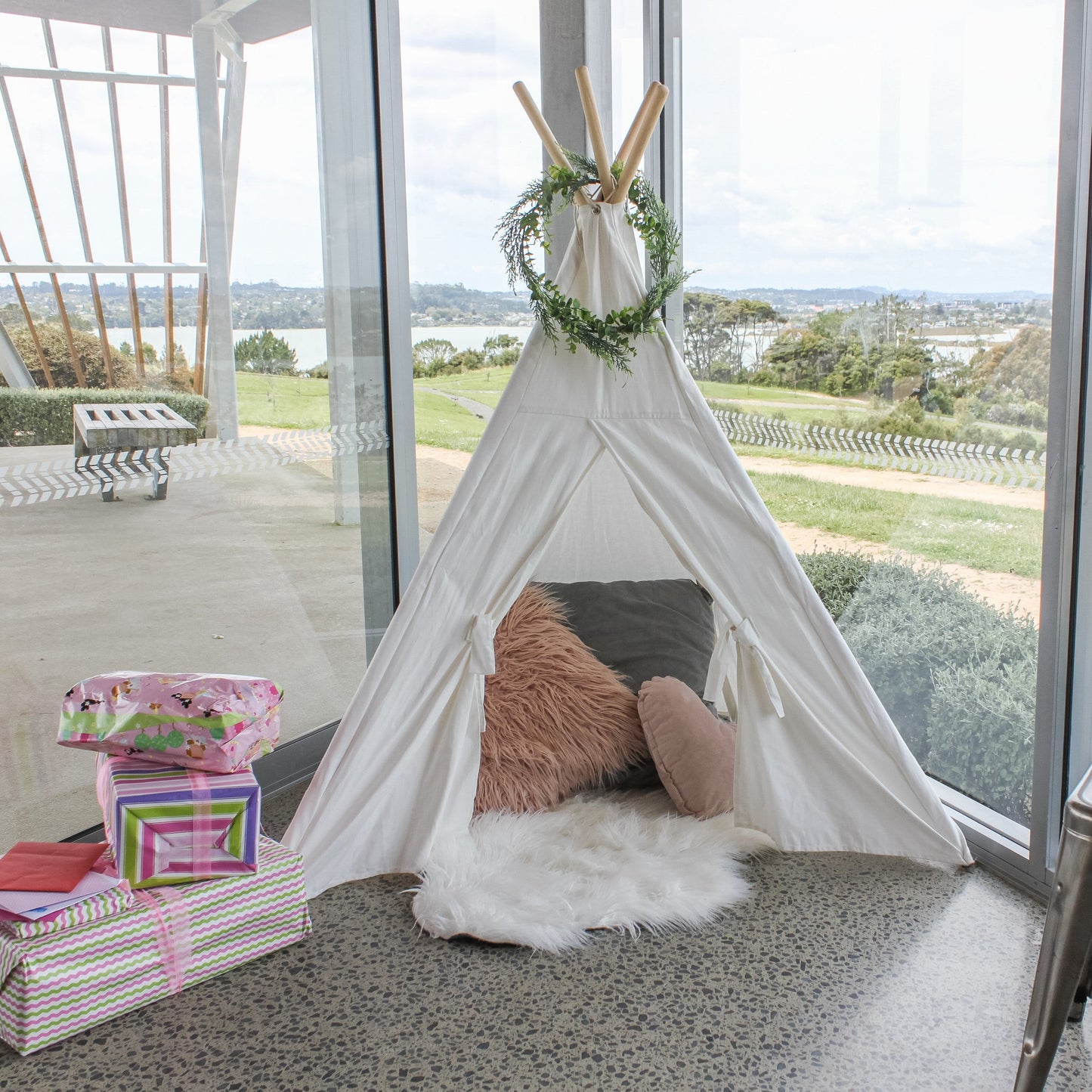 small tepee with cushions and foliage wreath