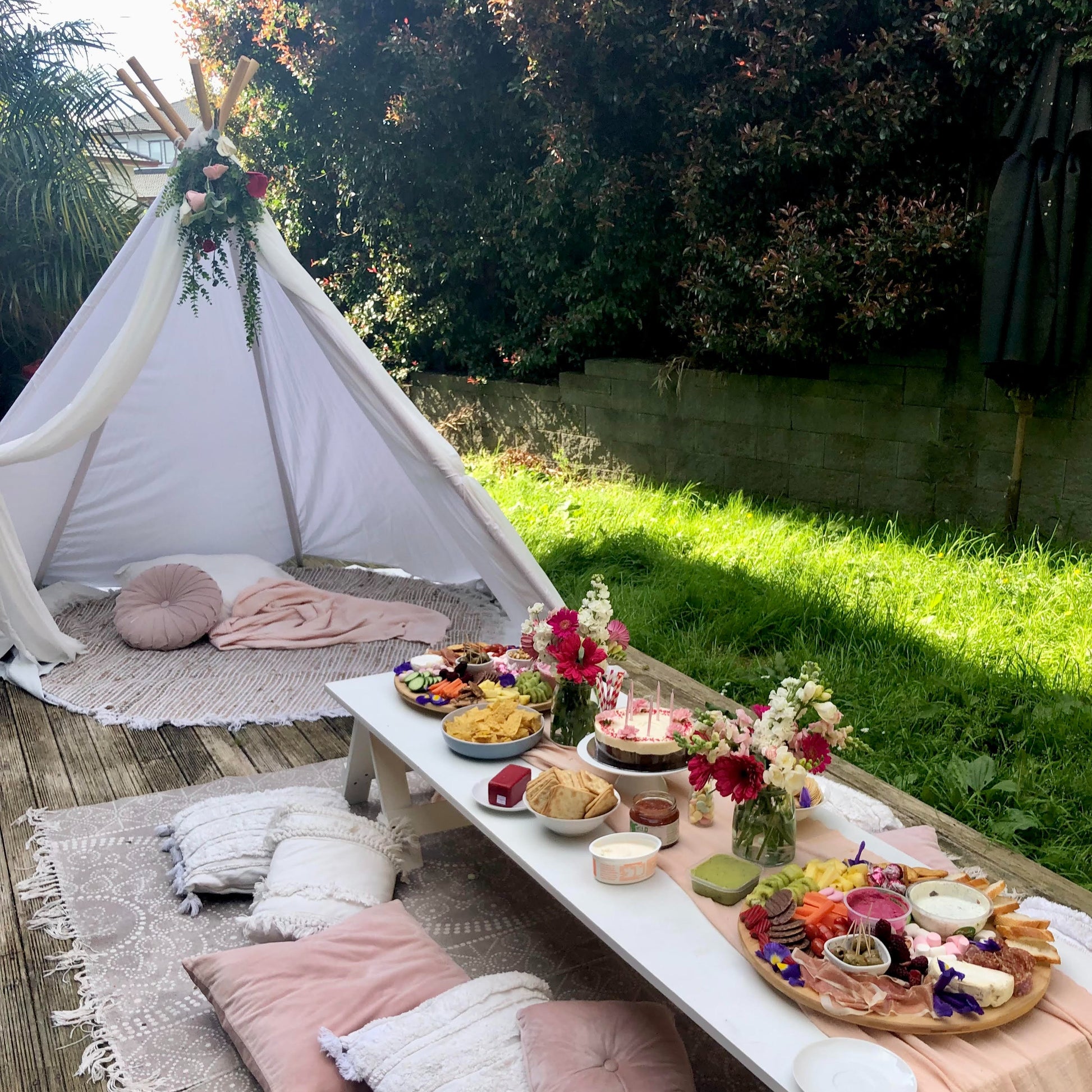 Large teepee with low picnic table and florals and cushions